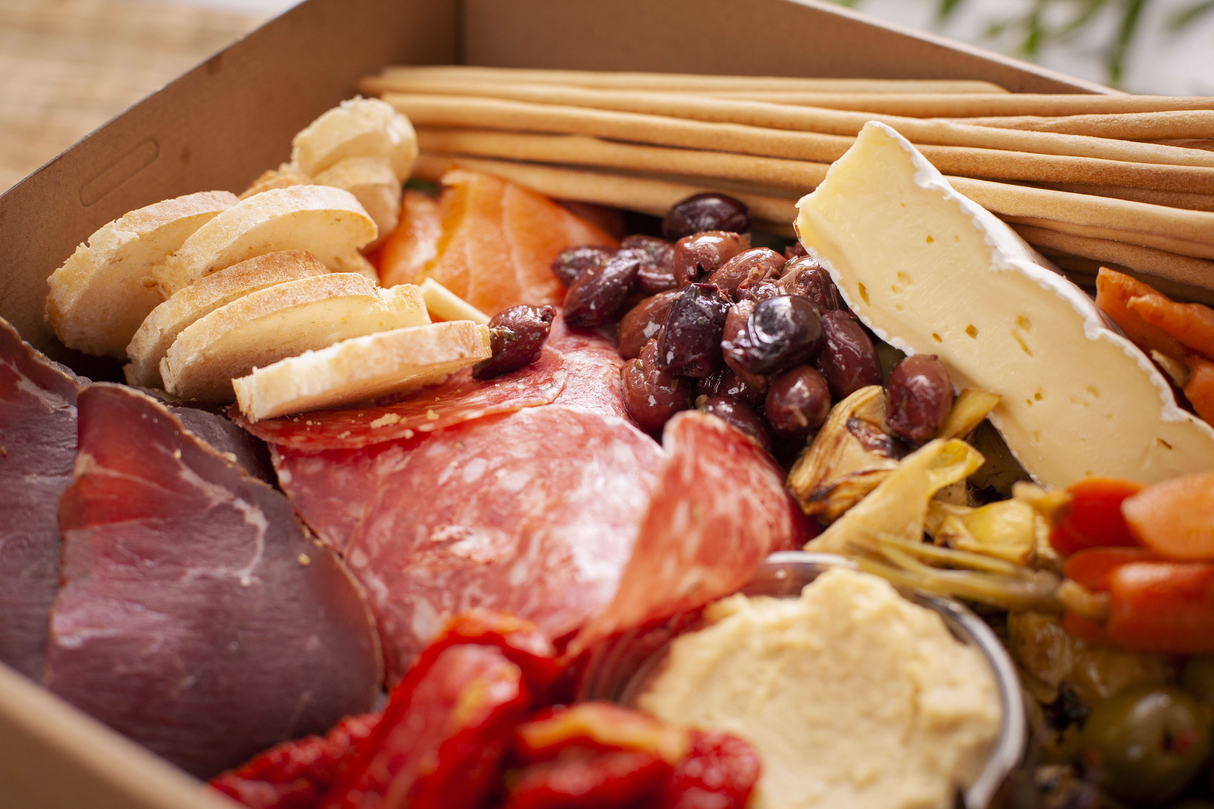 Close up of antipasto box, including Casalingo salami, bresaola, smoked salmon, marinated olives, artichokes, carrots, hummus, Tasmanian Brie, grissini, sliced baguette. Photo: Richard Jupe.