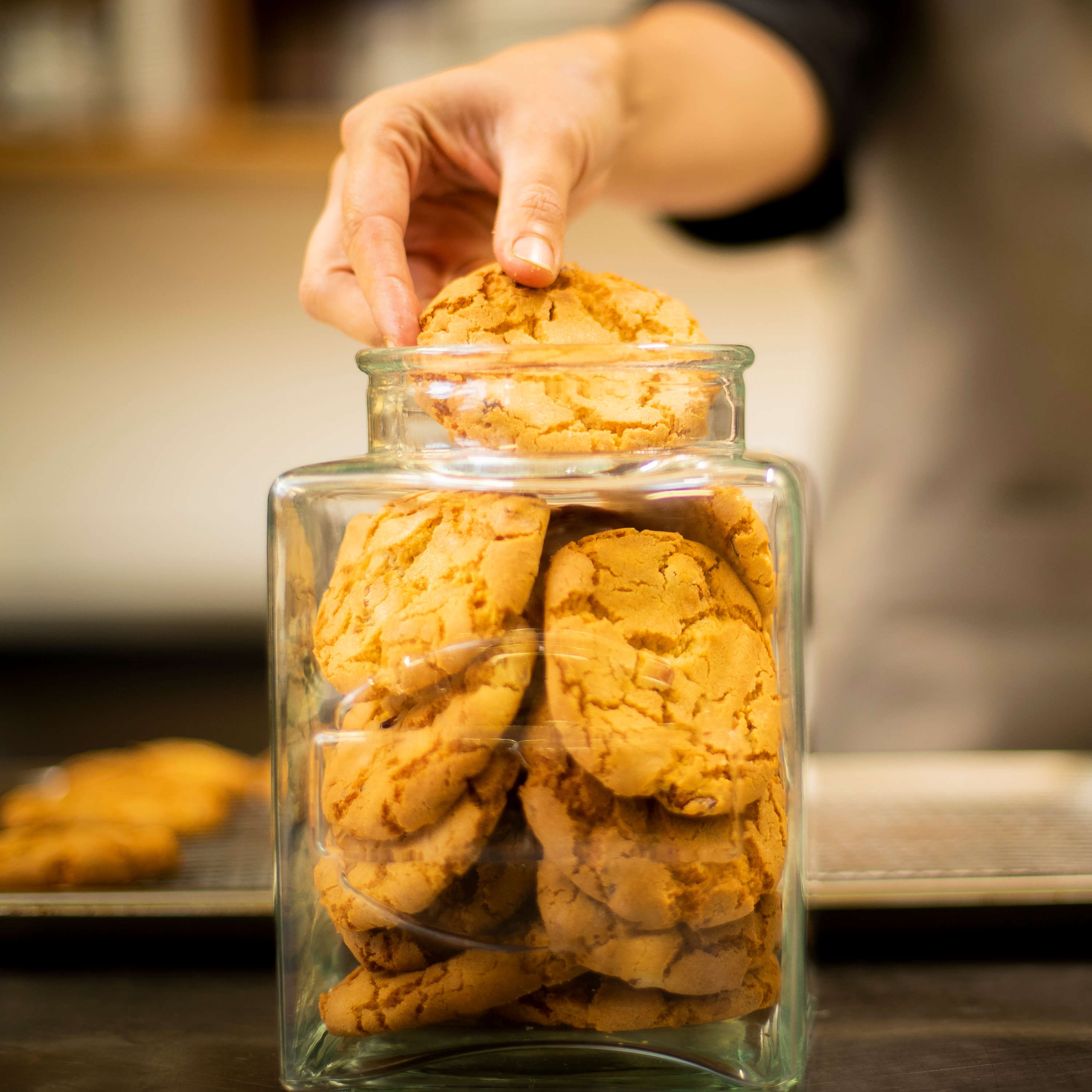 Close up of chef placing cookies into a glass jar. Photo: Richard Jupe.